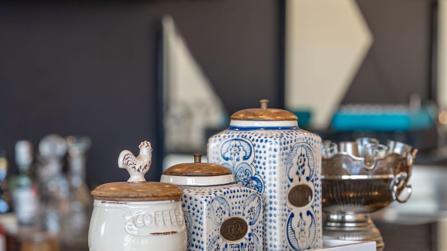 A close-up shot features a white tray holding a sugar dispenser, a small pitcher, and a napkin holder - Vishranti Resort, Dehradun.
