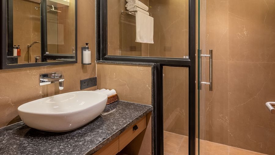Bathroom at vishranti Hotel, Dehradun featuring sink area, shower area, a mirror with ambient lighting.
