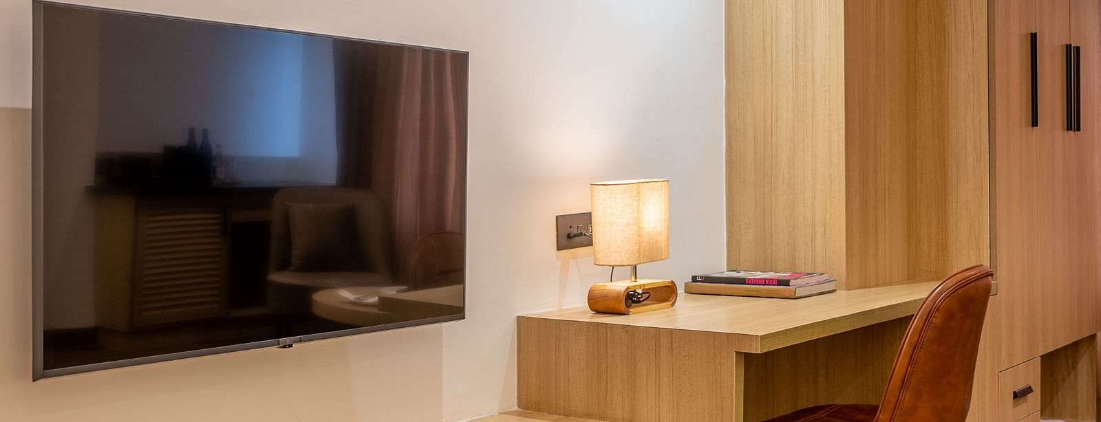 Interior of  a room at Vishranti Hotel, Dehradun featuring a work desk, chair and a TV.