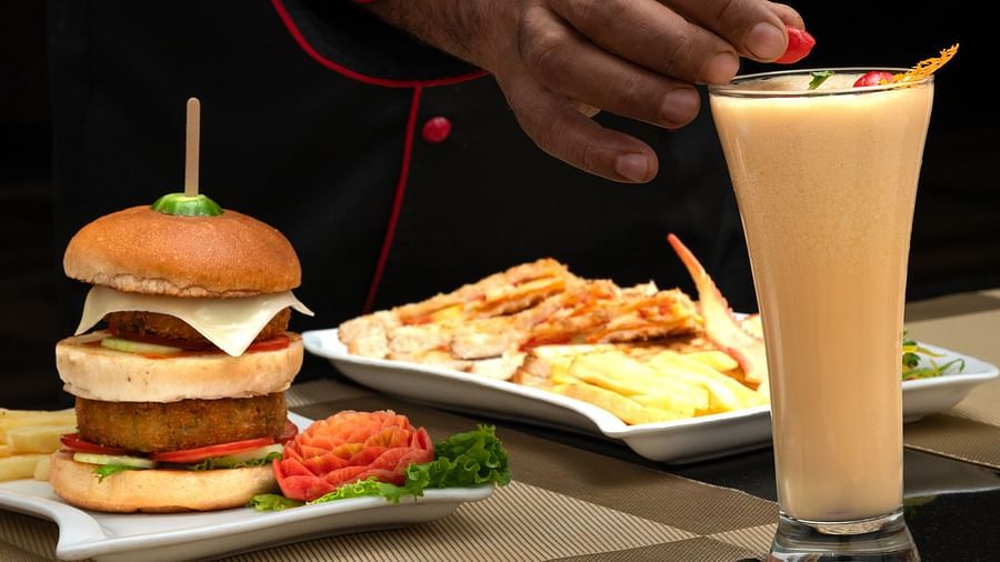 A close-up of a chef presenting a Burger, showcasing the attention to detail and quality of the food - Clarks Inn Express, Near Jammu Bari Brahmana Railway Station