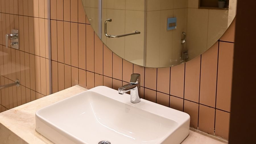 image of a the wash basin along with a big circular mirror at club charholi, pune