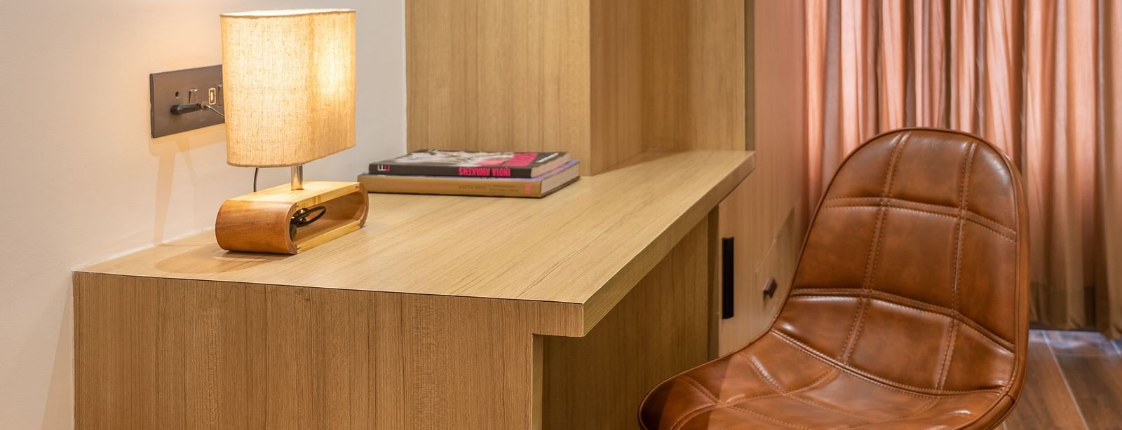 Close up of a work desk and chair arrangement with warm lighting at Vishranti Hotel, Dehradun