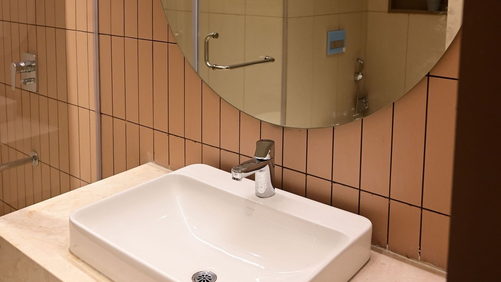 image of a the wash basin along with a big circular mirror at club charholi, pune