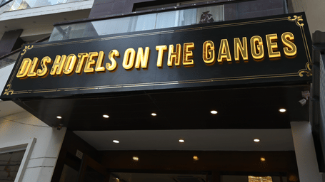 Exterior view of DLS Hotels on the Ganges, showcasing the multi-story purple building, the hotel signage in bold yellow letters, and the surrounding urban environment, giving a clear impression of the hotel’s façade
