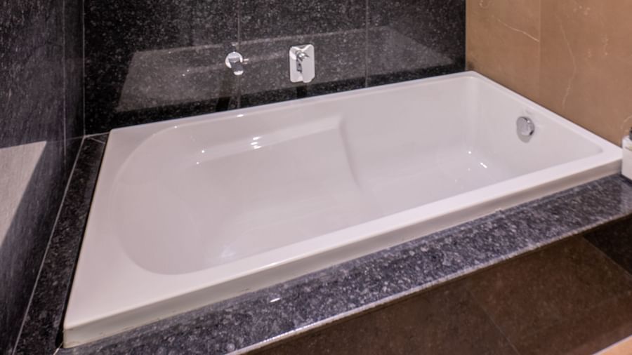 Shot of a white bathtub in Suite of Vishranti Hotel Dehradun with black marble walls.