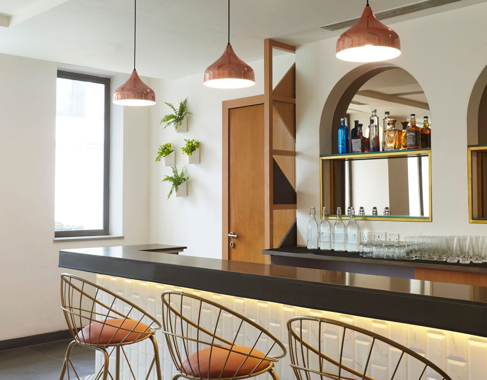 A close-up of the stylish bar counter and high stools at Monday Hotels Mahape, Navi Mumbai.