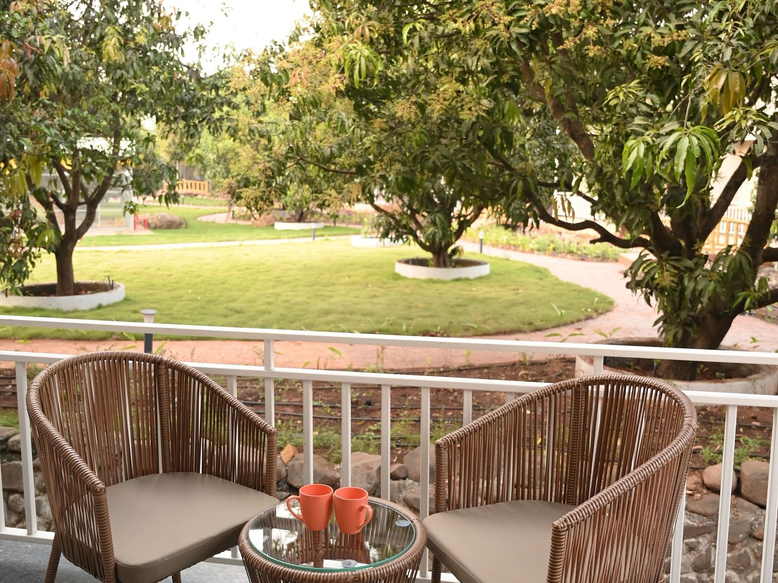 Two chairs on a patio with a garden view outside the Deluxe Cottage at Mango Leaf Lake Resort, Pune