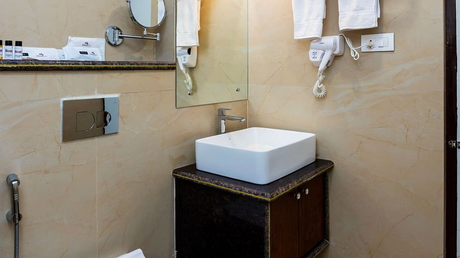 Modern bathroom with sink, toilet, towels, and wall-mounted amenities at Biznotel by Pride, Deoghar
