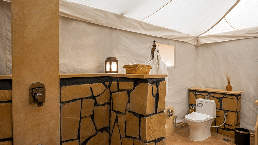 The commode, the shower and the aesthetically designed brick wall inside the washroom - Karwaan Jaisalmer