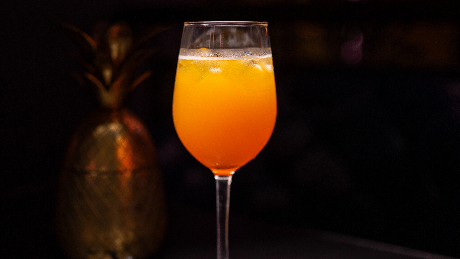 A glass of drink set against a dark background with dim lighting, creating an elegant ambiance at Hotel Moti Palace.