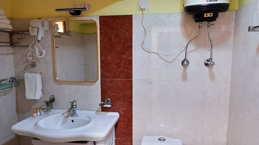 Deluxe rooms bathroom equipped with a washbasin, mirror, geyser, and western toilet1