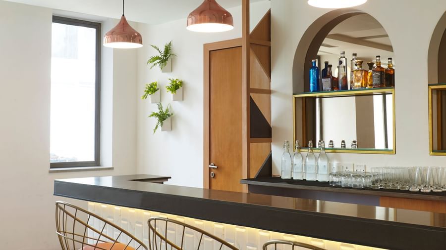 A close-up of the stylish bar counter and high stools at Monday Hotels Mahape, Navi Mumbai.