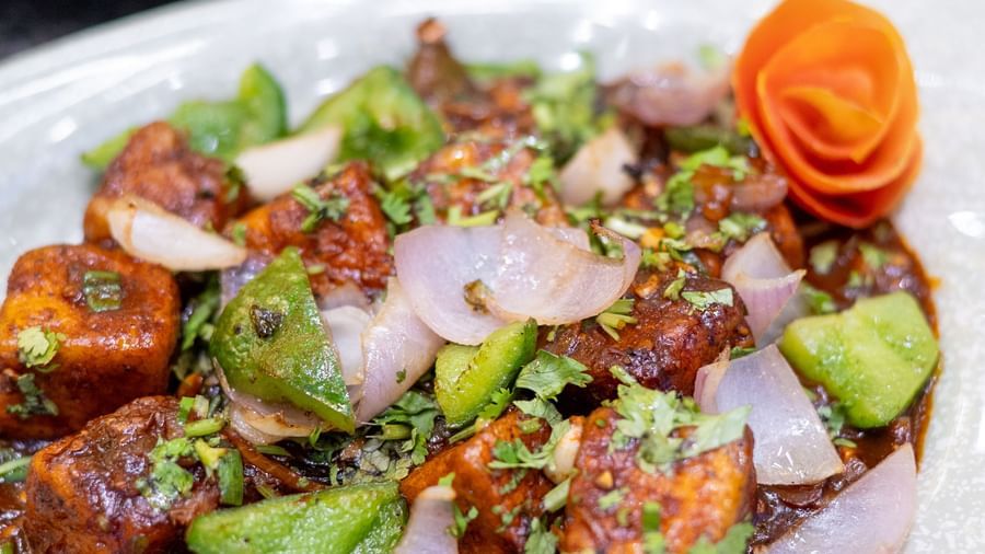 A plate of chilli paneer with diced onions and peppers is served at Pravasa Stay, Shirdi.