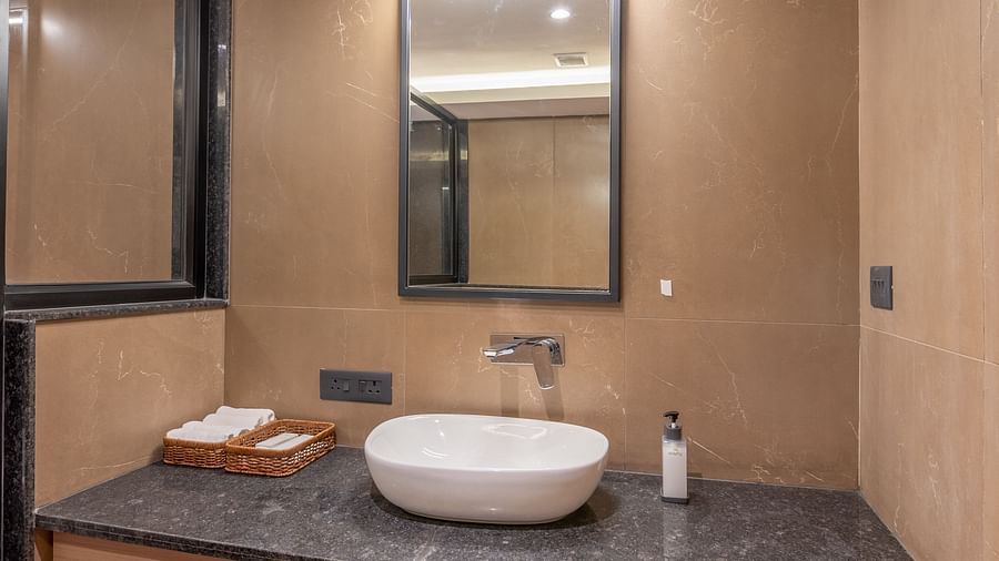Bathroom at vishranti Hotel, Dehradun featuring sink area, a mirror with ambient lighting.