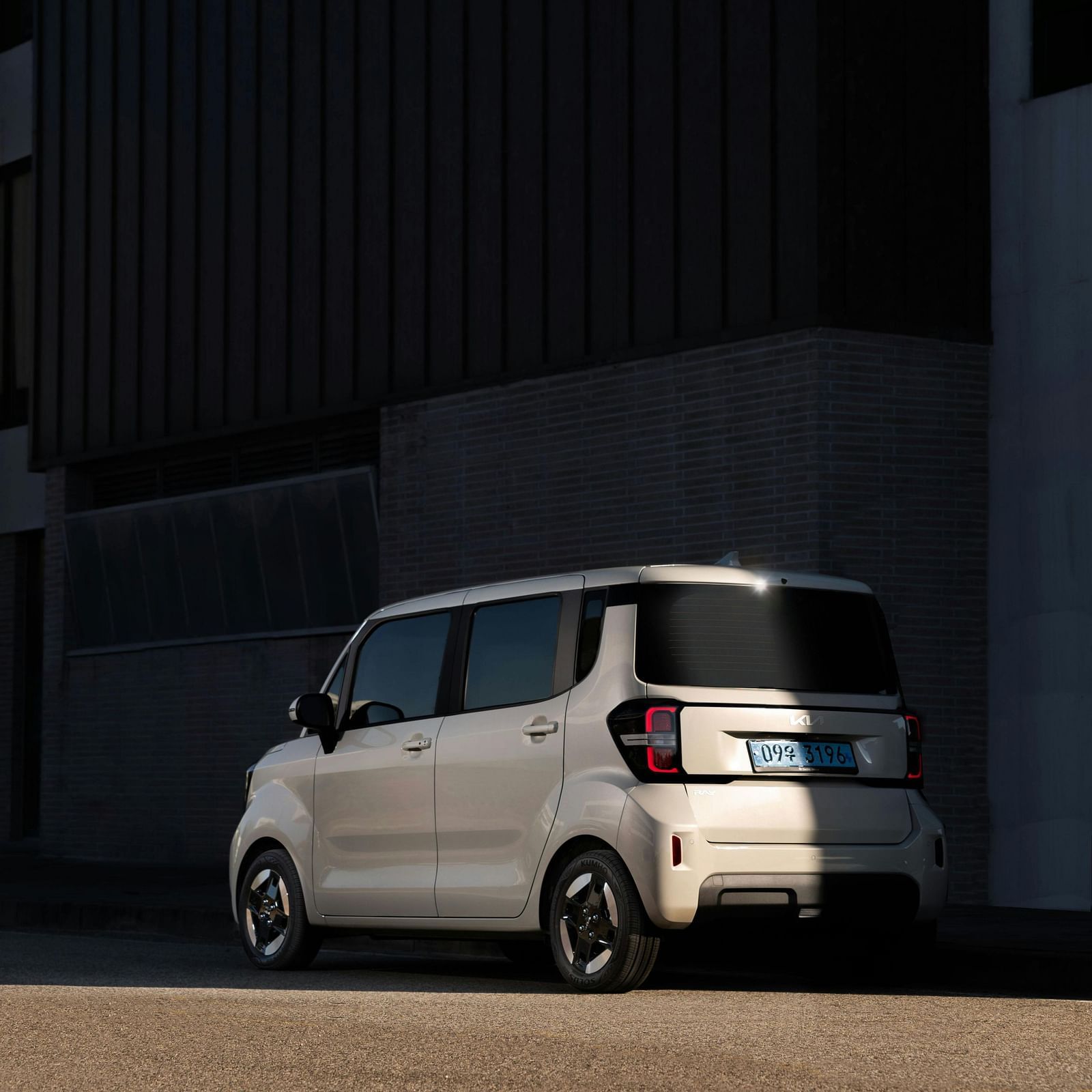 A white car parked near a building wall on a sunny day.