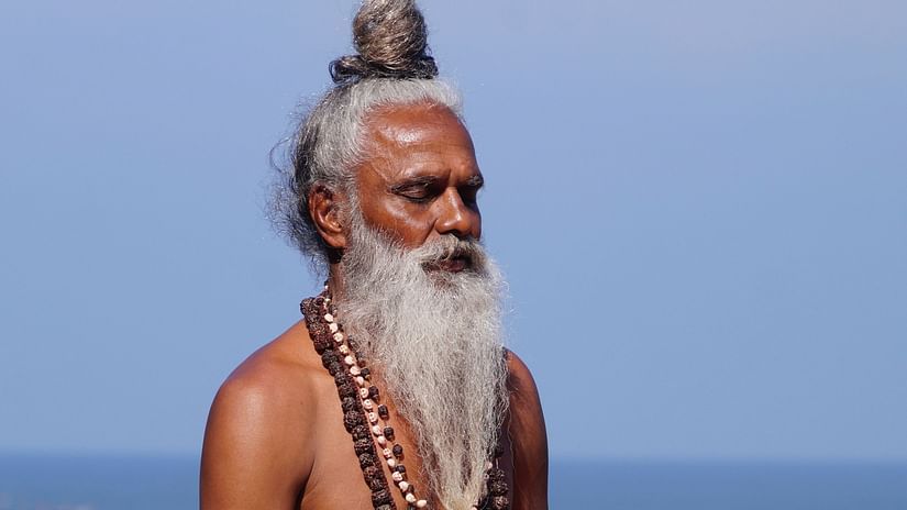A man wearing saffron dhoti and meditating