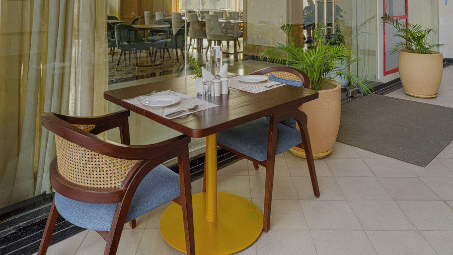 An indoor dining area with a glass enclosure and a wooden table with several chairs.