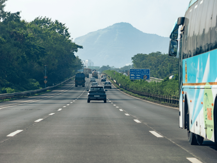 A scenic highway with vehicles travelling against a backdrop of hills in Navi Mumbai.