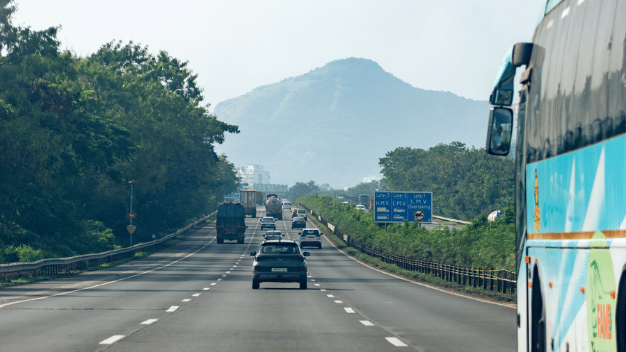 A scenic highway with vehicles travelling against a backdrop of hills in Navi Mumbai.