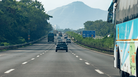 Cars and bus travelling on an empty express highway during the day time.