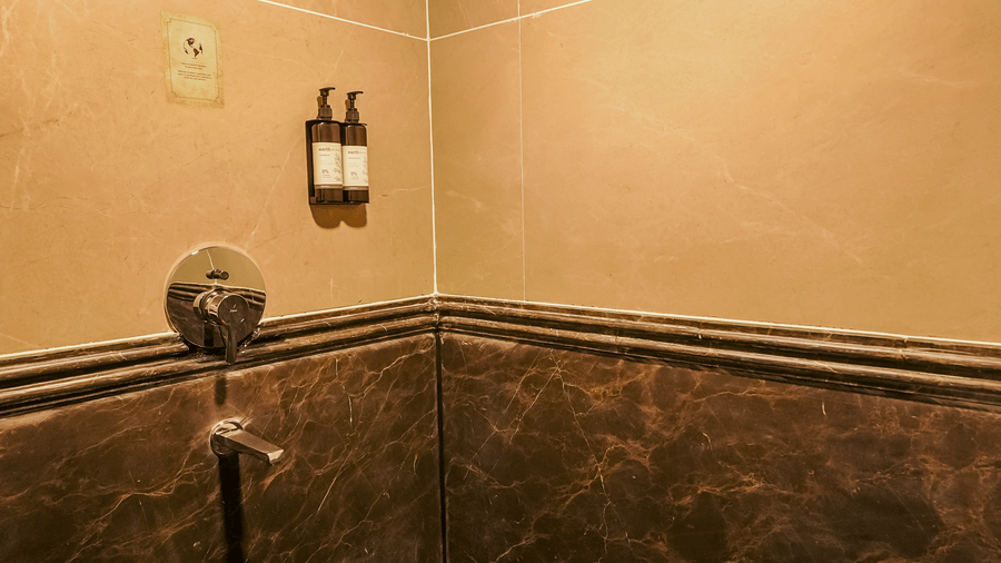 The claasic room bathroom at BluSalzz Terrah Hills Resort, Dalhousie, featuring wall mounted shower head, 2 soap dispensers, and a water tap.