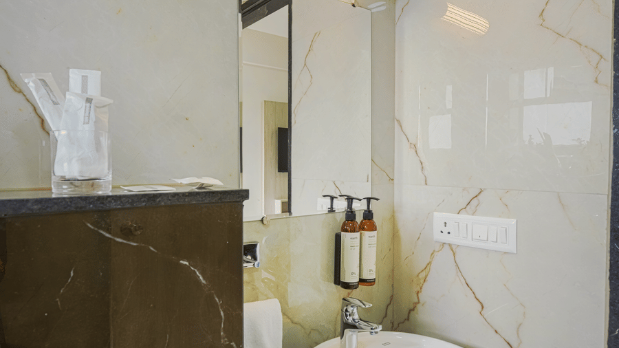 A hotel room bathroom at Urban Suites by BluSalzz, Jaipur, with a sink basin, mirror, and toilet.