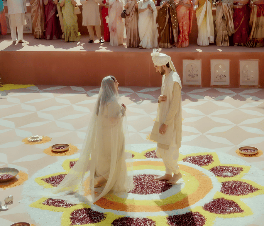 Charvi & Dhruv standing at rangoli setup inside Umaid Palace courtyard during wedding ceremony.