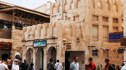 People walking on a paved road in a market with a building in the backdrop