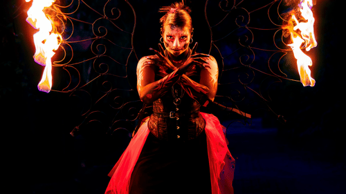 A performer skillfully juggling flaming torches on a dark stage.