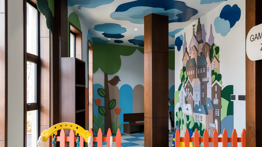 An indoor children's playroom featuring a blue and grey checkered floor, a small yellow slide, and a colourful wall mural at Hotel Sonar Bangla, Ajodhya Hills.