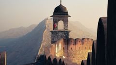 Old stone fortress near stairs and mountains under blue sky