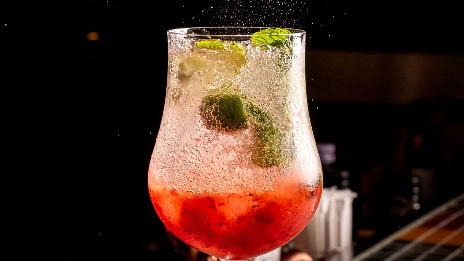 A close up shot of a cocktail drink placed on a table inside the bar - An overview of the seating arrangements inside a bar - Night Hotel Bangkok.