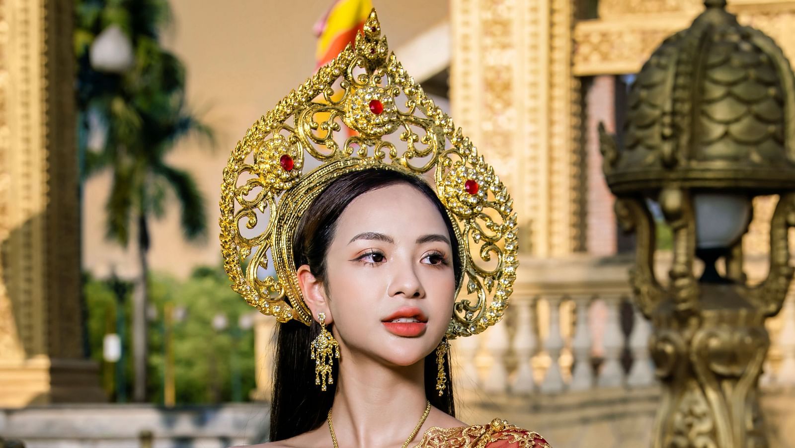 A close up of a woman wearing traditional thai dress made of thai silk while posing for a picture.