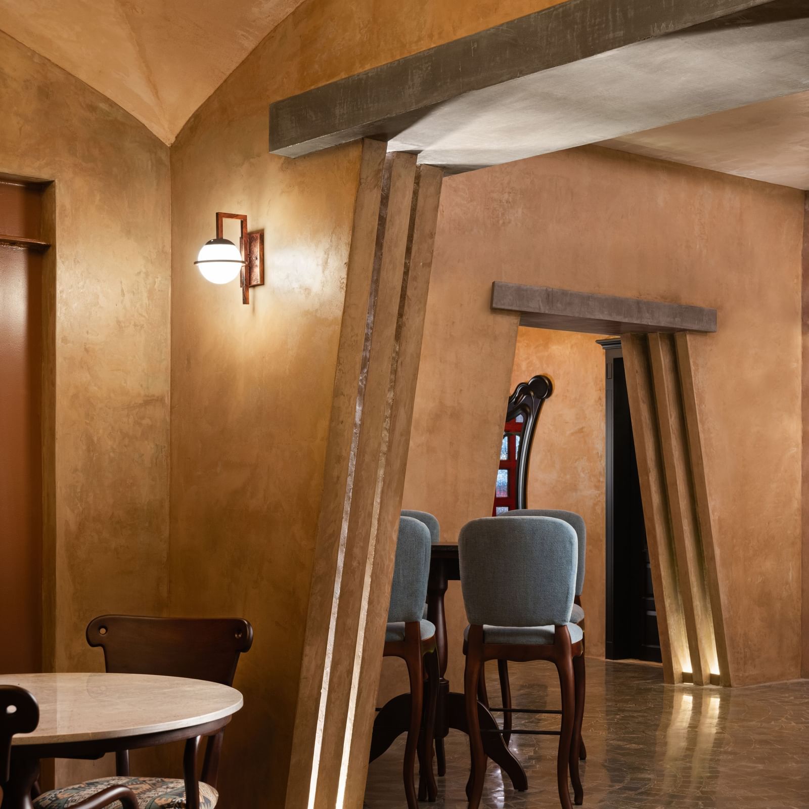  A warmly lit hotel hallway at Shilton International, Kochi, with curved walls and elegant seating, leading to an inviting entrance.