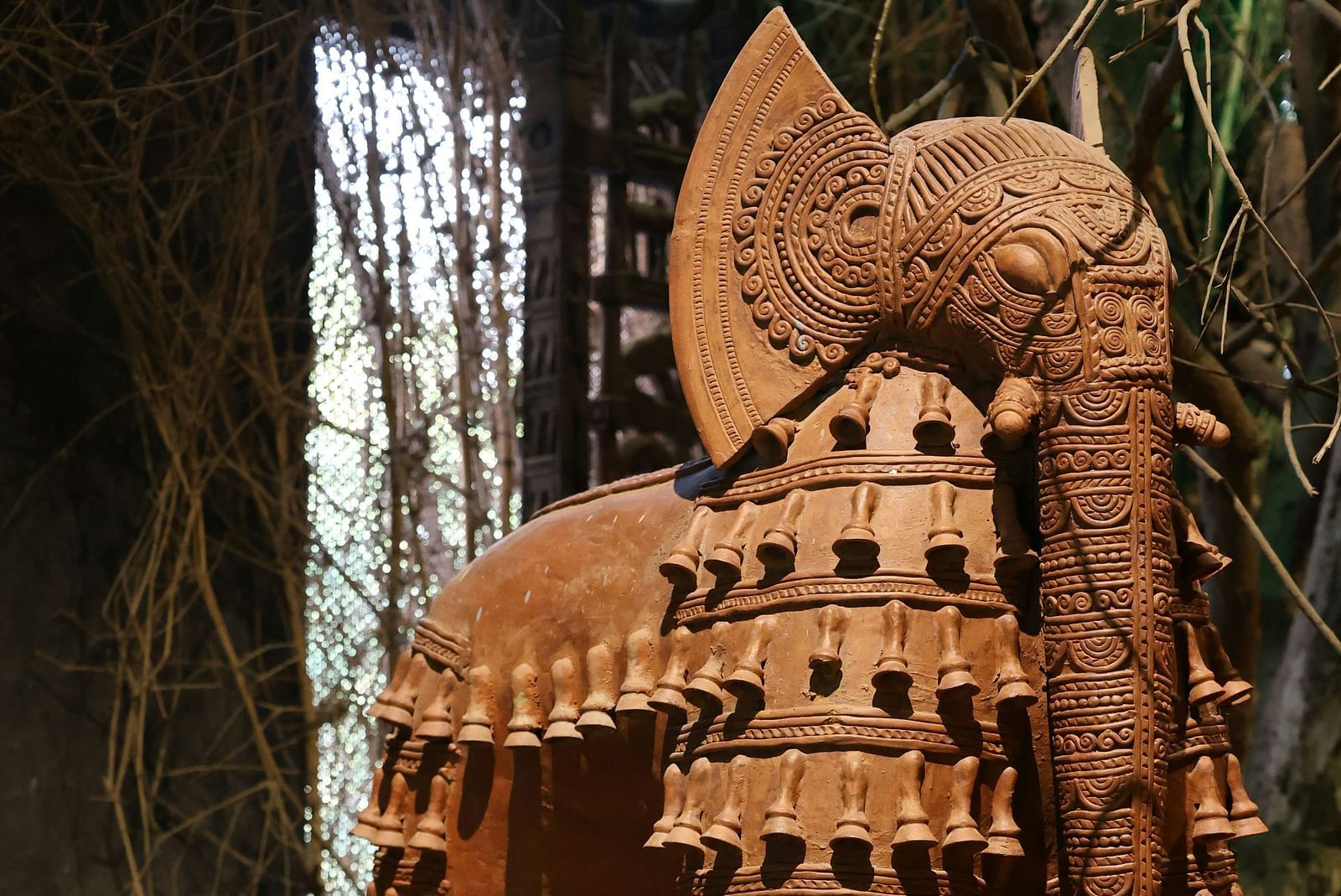 An image of a terracotta sculpture of an elephant adorned with intricate designs and patterns, surrounded by smaller elephant figurines, all showcasing exquisite craftsmanship - Kumarakom