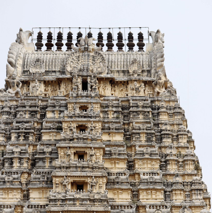 A view from below of a temple's facade with intricate art on the exterior of the roof in Tirupati.