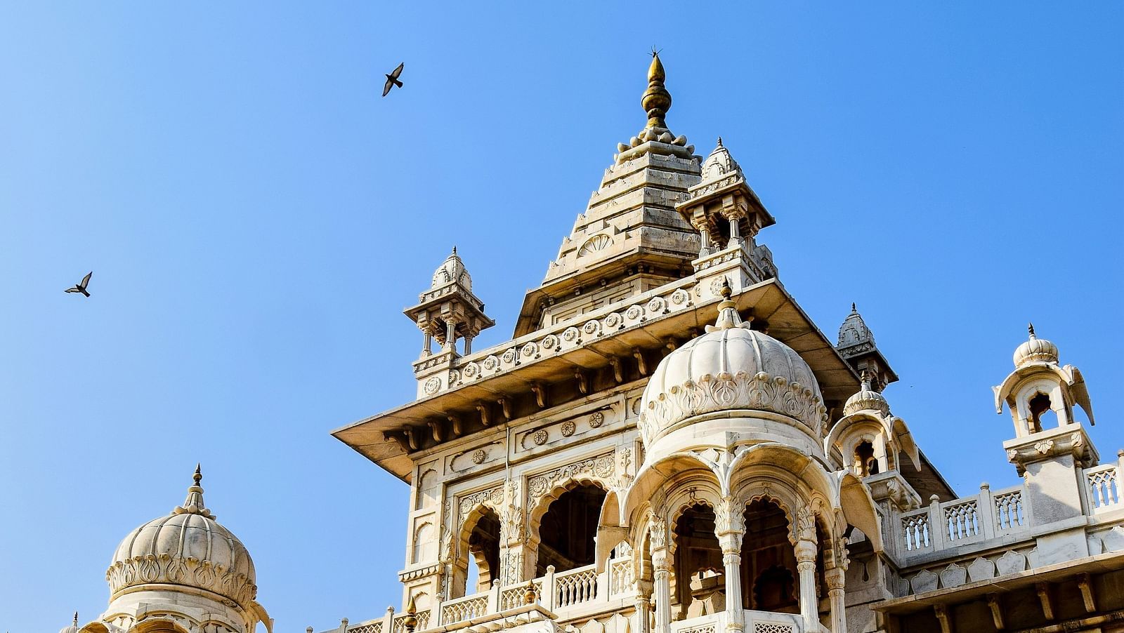 An far out view of a temple in jodhpur with birds flying in the background