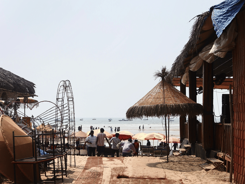 Scenic view from a beach hut in Goa with umbrellas and people enjoying the sandy shore