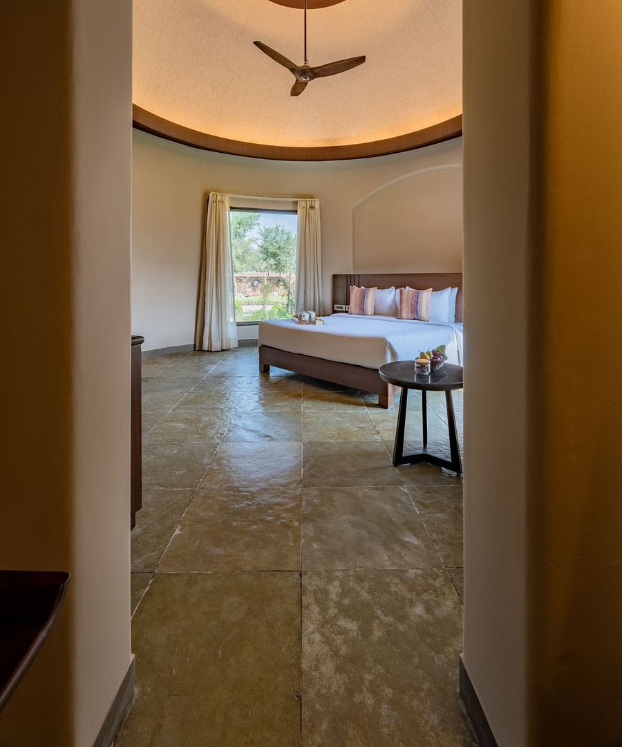 A sneak peak image of a room with bedroom with a tea table and a large window from where sunlight is flooding - Ananta Spa and Resort, Ajabgarh