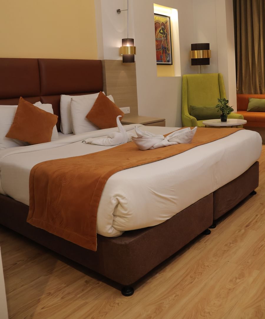 Double bedroom with orange runner, white pillows, wooden headboard and modern ceiling at Best Western, Vrindavan.