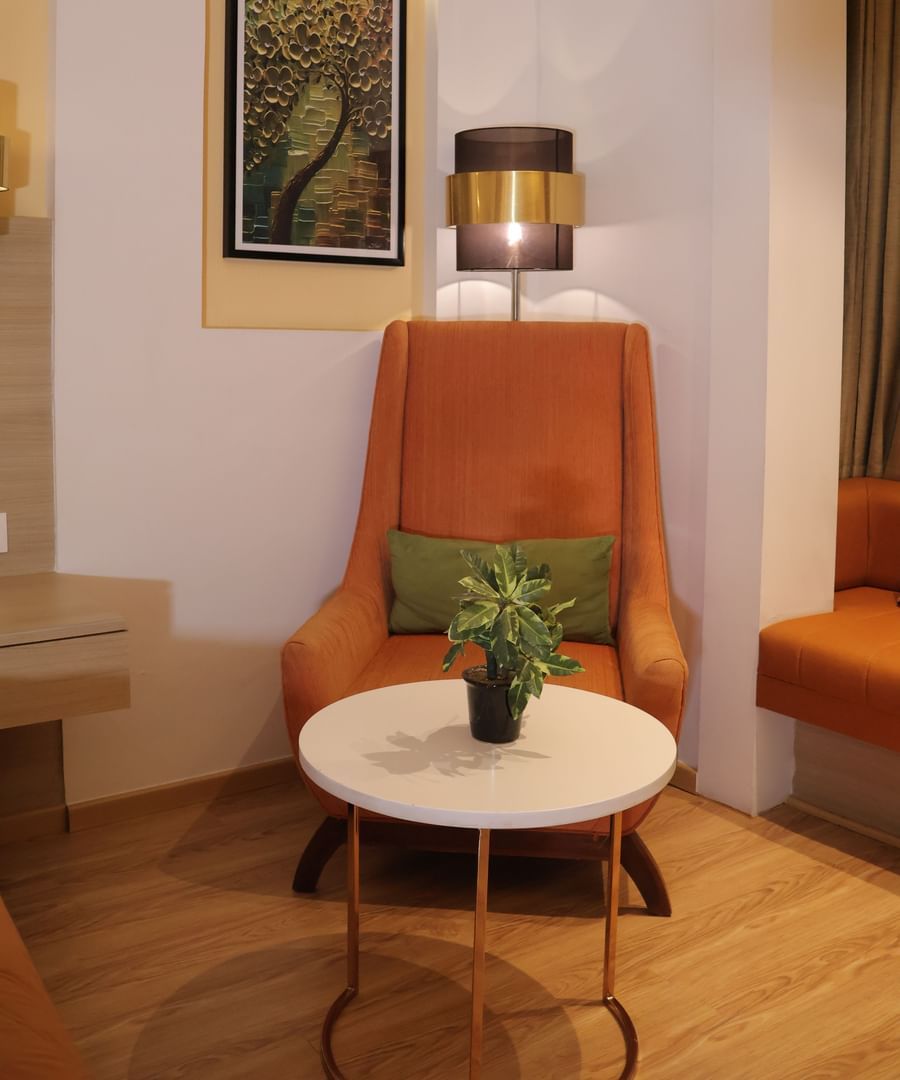 Lounge seating with white round table, green cushioned chair and framed artwork on wall at Best Western, Vrindavan.