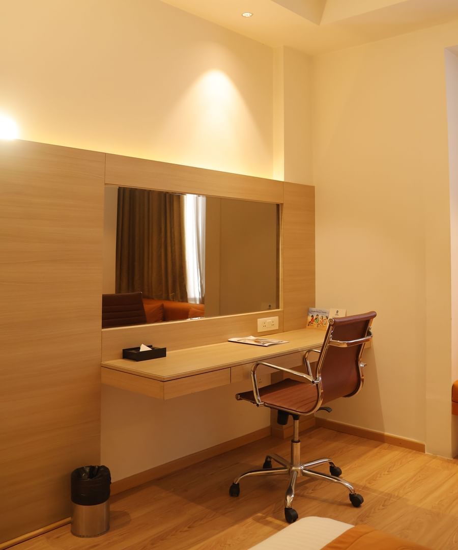 Hotel room desk area with wooden panelling, office chair and built-in mirror at Best Western, Vrindavan.