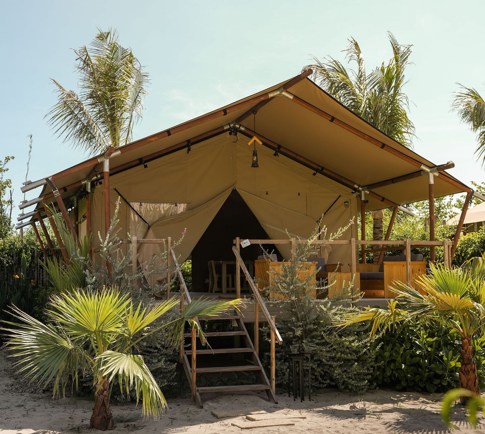 A front-facing view of the Mindful Tent at WoCAL Retreat Ke Ga, featuring a wooden deck, steps leading to the entrance, and an inviting outdoor space surrounded by greenery.