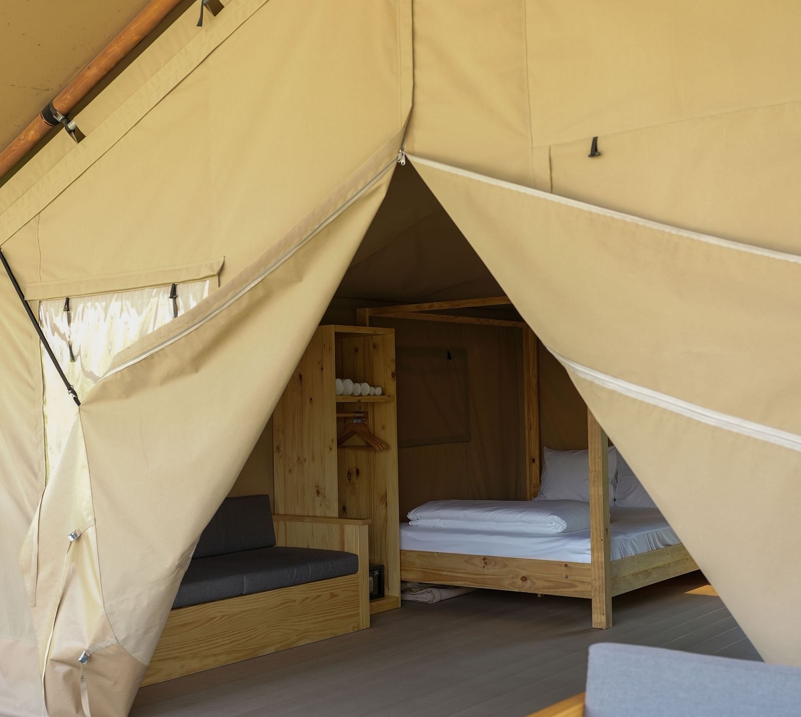  The entrance of the Mindful Tent at WoCAL Retreat Ke Ga with canvas curtains tied open, revealing a interior with wooden chairs and a table.