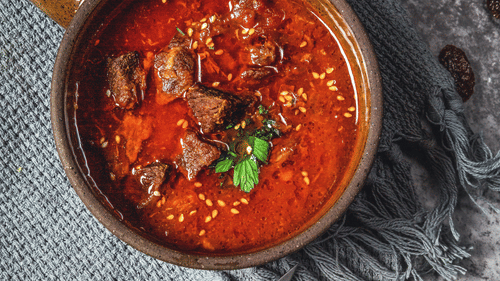 image featuring a bowl of Red meat curry topped with coriander leaves