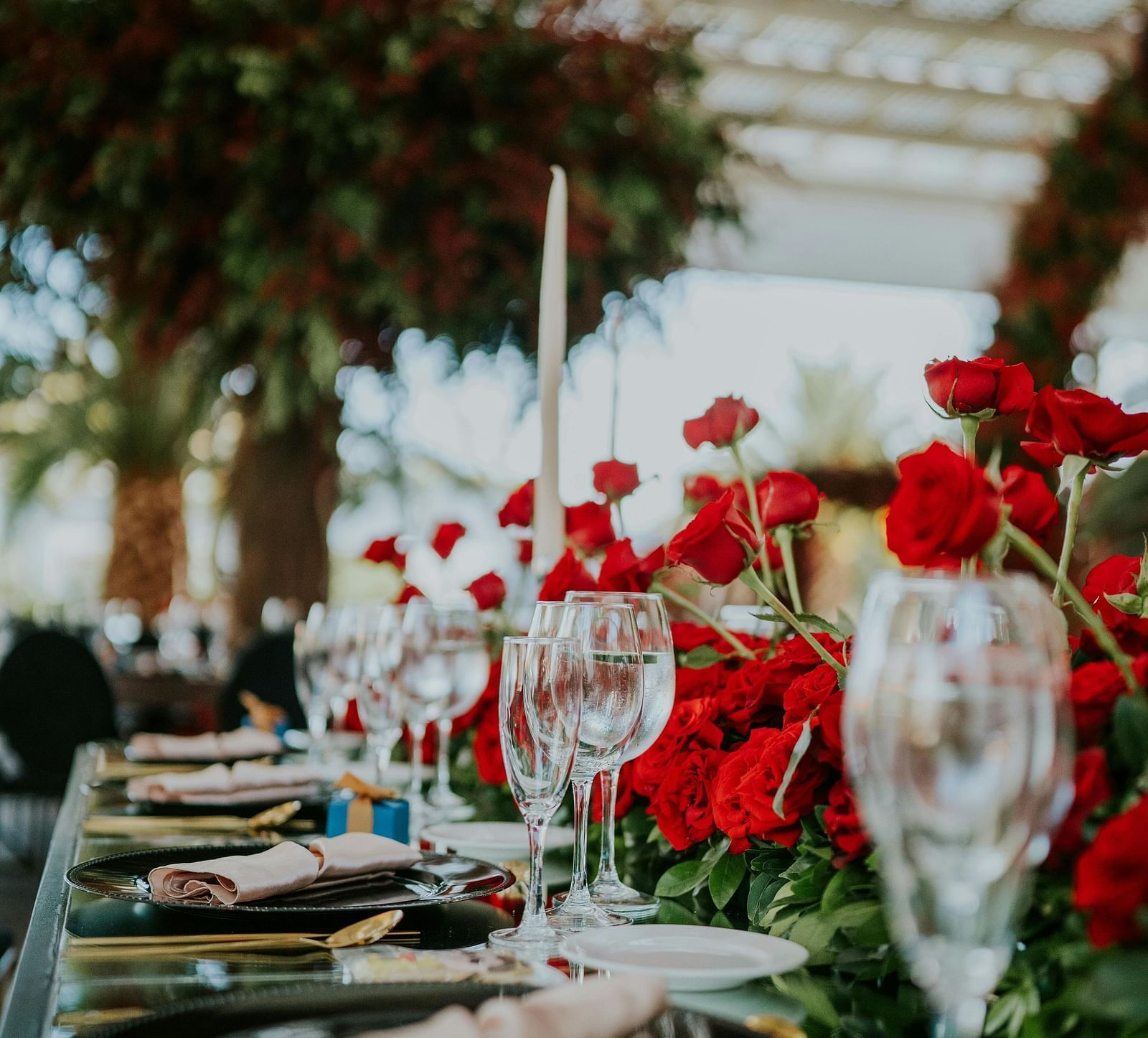 An image of a table where dishes are placed along with hand towels, cutlery, and glasses and decorated by roses
