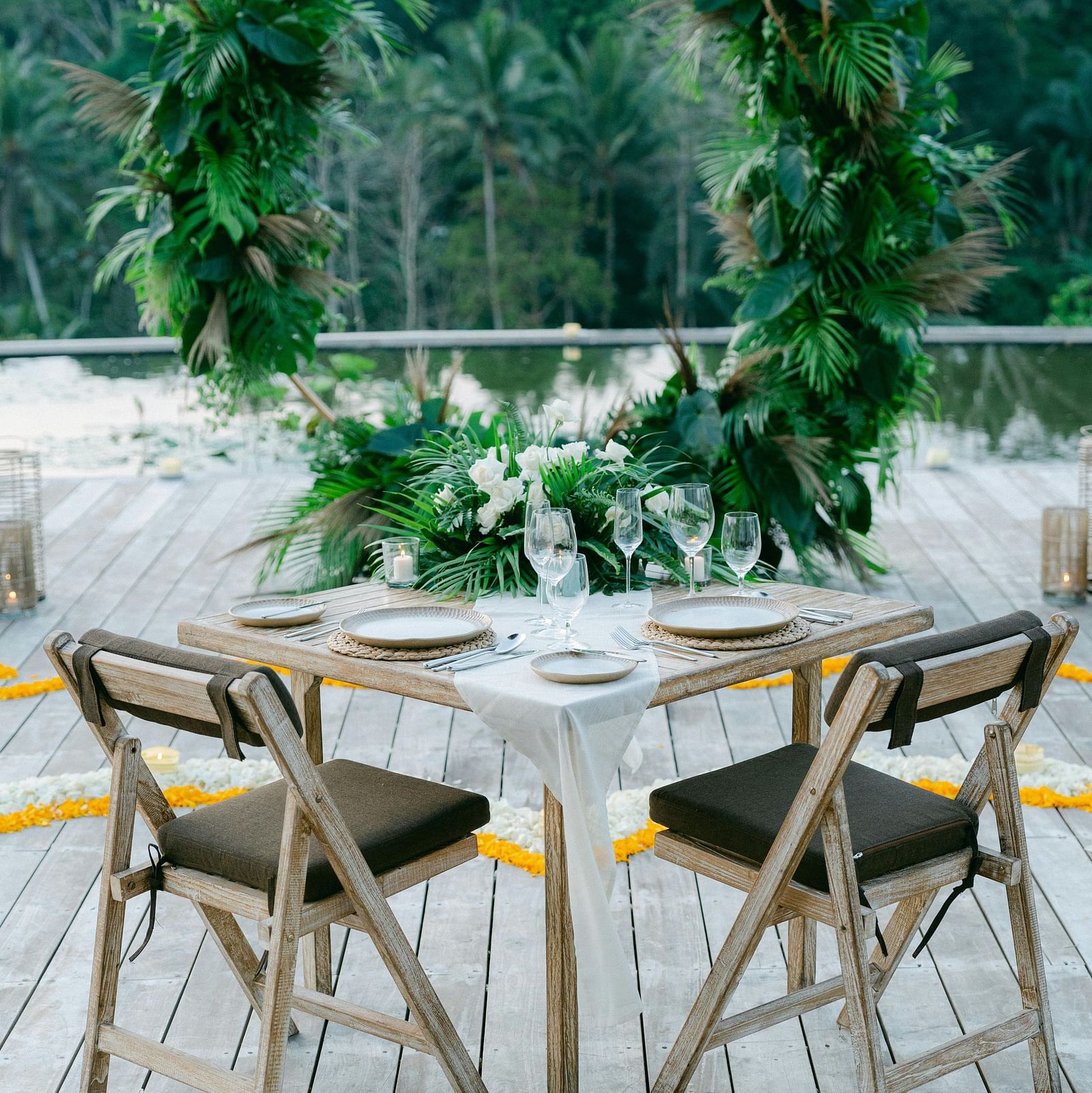 A balcony with a table and chairs overlooking lush trees.