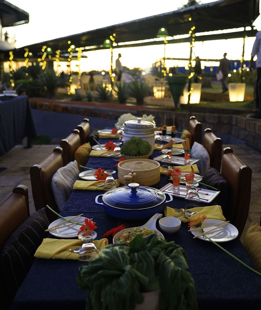 An image of a dining area featuring several tables with food items and chairs on either side  Polo Orchid Resort, Cherrapunji