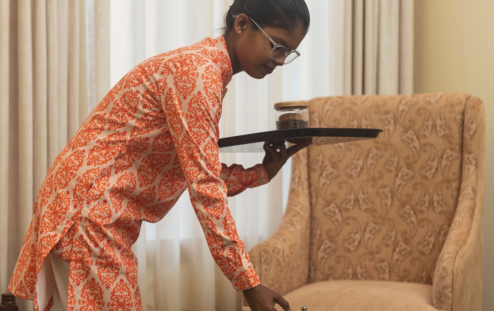 A woman in traditional Indain attire serving food in a room at Kesar Bagh Palace.
