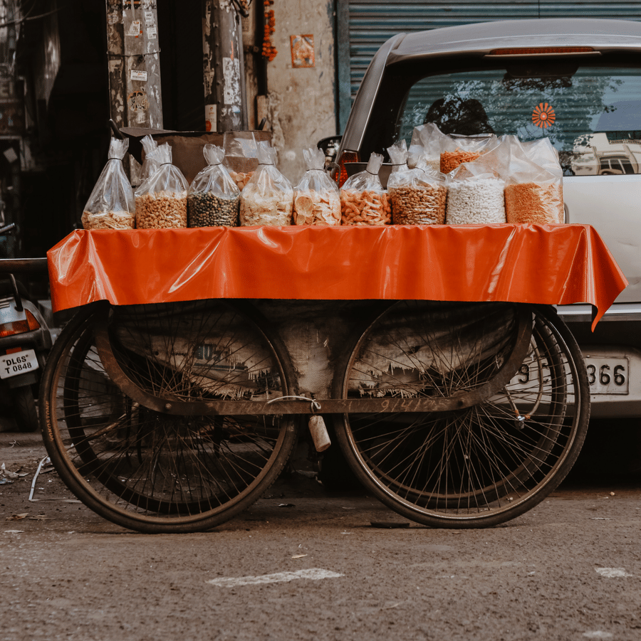 A street cart with metal wheels, with bags of spices and grains kept on a cloth